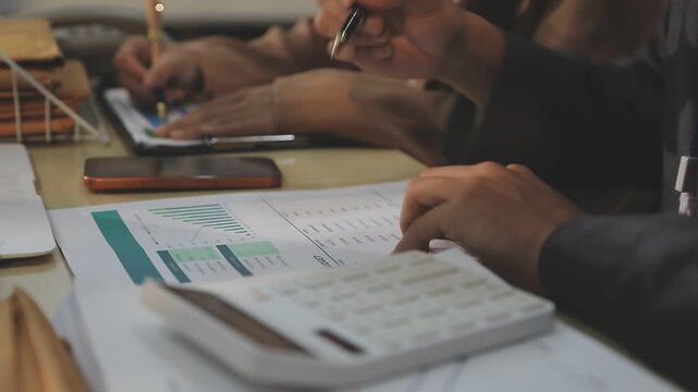 Close up of businessman or accountant hand holding pen working on calculator to calculate business data, accountancy document and laptop computer at office, business concept