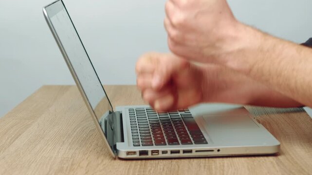 White Male Hands Punching Laptop Screen, Closeup On Wood Desk With Visible Keyboard And Open Aluminum Case,