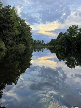 Symmetric Sunset Reflection on Glassy Pond with Blue Clouds