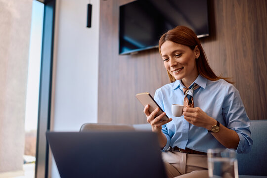 Happy businesswoman using smart phone on coffee break in office.
