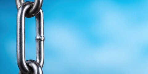 Naklejka premium Close-up of a strong metal chain hanging against a soft blue blurred background