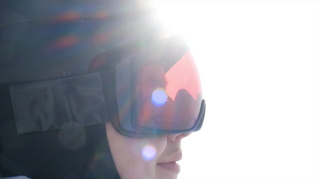 Close up head of skier in helmet and ski goggles smiling and looking forward anticipating excitement and adrenaline before descent. Happy snowboarder ready to start. Winter sport and active lifestyle