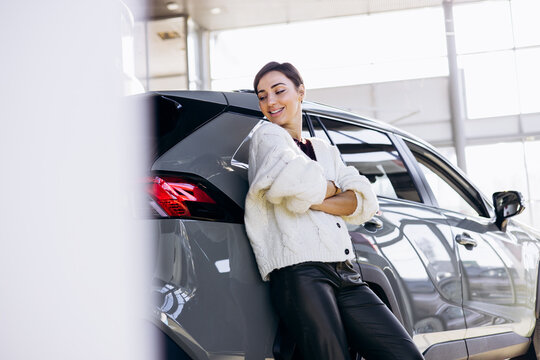 Woman choosing a new car in a dealership showroom. Customer inspecting vehicles, making purchase decision, modern lifestyle and transportation concept.