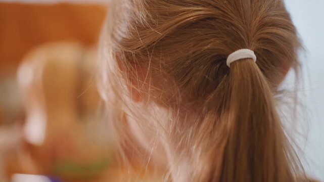 Young caucasian girl with ponytail closeup profile in warm kitchen, soft sunlight backlighting hair and catching tiny dust motes, blurred pumpkin and pumpkin pie in background suggesting seasonal