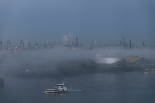 Hafengel&auml;nde mit Industrieanlagen und F&auml;hre im dichten Nebel bei D&auml;mmerung