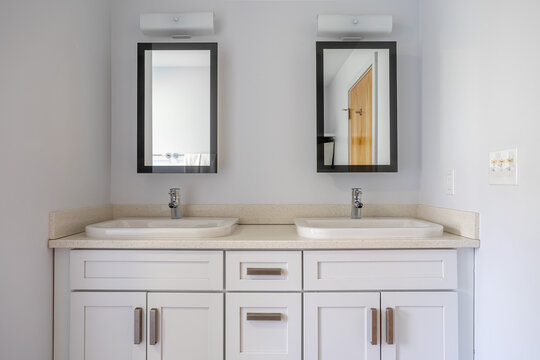 Modern double vanity bathroom with white cabinets, twin mirrors and vessel sinks