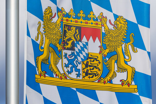 Detailaufnahme einer bayerischen Staatsflagge mit wei&szlig;-blauem Rautenmuster und gro&szlig;em Staatswappen an einem Fahnenmast. 