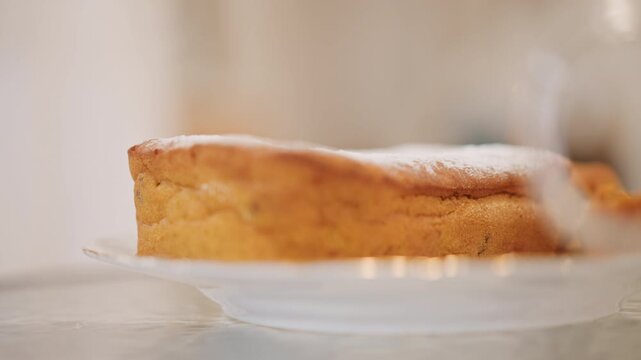 Sweet pumpkin dessert with powdered sugar dusting. Delicious pumpkin pastry served on glass with warm lighting. Homemade pumpkin pie slice resting on glass plate with soft kitchen illumination