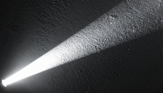 Rayo de luz brillante y enfocado iluminando una superficie oscura y texturizada en la noche.