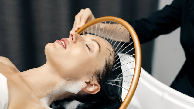 Japanese head spa treatment for relaxation, gentle water flow massaging young woman&rsquo;s scalp.
