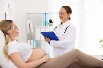 Fototapeta premium Pregnant woman having appointment with doctor in clinic