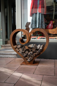 Rusty corten steel heart-shaped firewood holder in front of shop window, Luxembourg