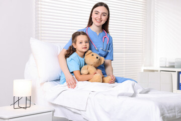 Obraz premium Doctor and little child with toy on bed in hospital