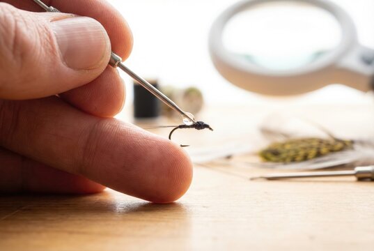 Applying a tiny drop of head cement to the thread wraps of a handmade fishing fly with a bodkin