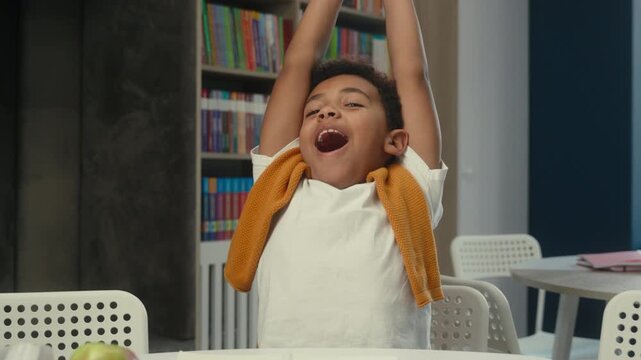 African American little boy kid yawning stretching smiling tired with studying learn writing homework at library child son schoolboy write yawn stretch in school sleepy schoolkid learning schoolwork