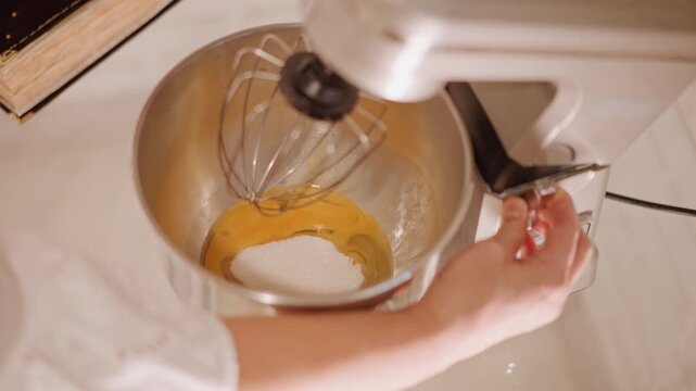 Stand mixer mixing pumpkin pie batter, closeup of hands adjusting speed and whisk attachment in warm kitchen light home baker blending yolks, sugar and spices into creamy filling for holiday dessert,