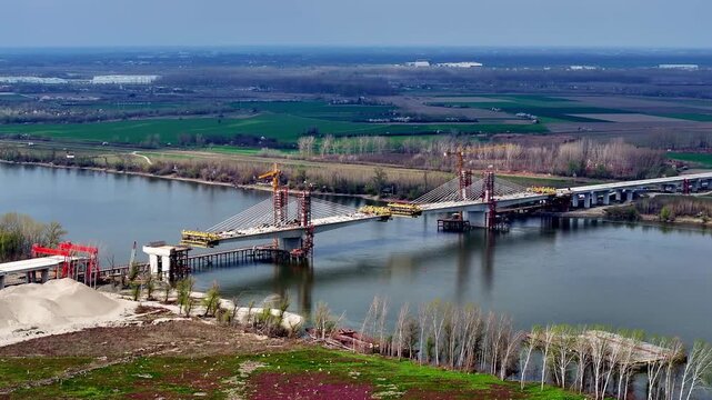 Large-scale construction of a modern cable-stayed bridge with tall tower cranes over a wide river