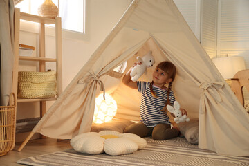 Little girl playing with toys in wigwam at home © New Africa