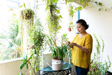 Woman tending plants on balcony.