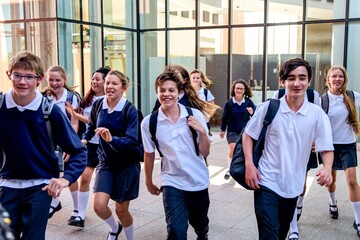 Joyful students leaving school building.