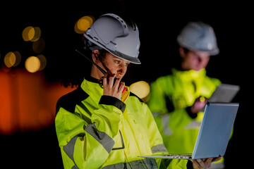 Industrial teamwork concept. Male and female workers checking data on a computer during a night...
