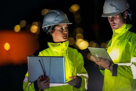 Focused professional working late on a computer in a dark office. Analyzing critical energy data or software during a blackout or shortage for essential business operations.