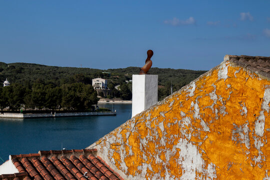White chimney and orange textured wall with sea view in Menorca