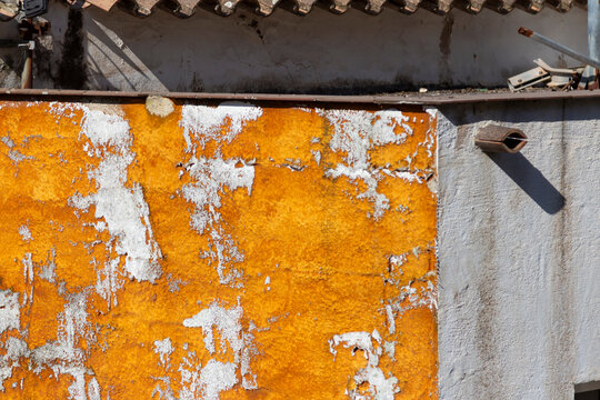 Textured wall with peeling orange paint and shadow in Menorca