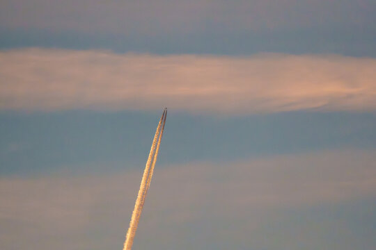 Airplane contrail in golden sunset sky with copy space