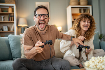 Happy couple enjoying exciting video game competition at home © Migma_Agency