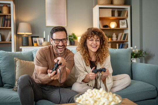 Happy couple laughing and playing video games at home