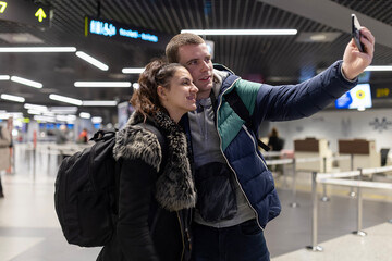 Fototapeta premium Young couple taking travel selfie at airport