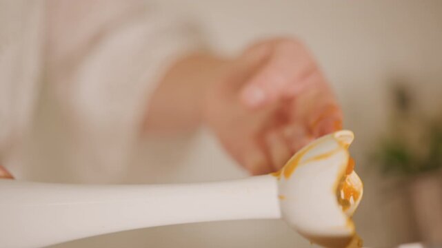 Hand sampling warm pumpkin mixture. Closeup of hand tasting sweet pumpkin stuffing in warm kitchen. Intimate shot of finger tasting velvety orange pumpkin filling with cozy kitchen ambiance
