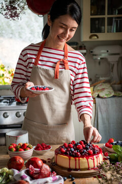 Joyful baker decorating berry cheesecake