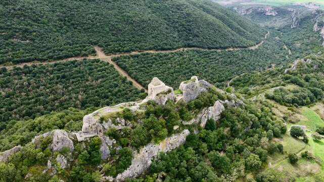 Vista a&eacute;rea cinematogr&aacute;fica de una fortaleza medieval en ruinas sobre un escarpado risco, con muros de piedra dominando el paisaje y evocando historia y car&aacute;cter.