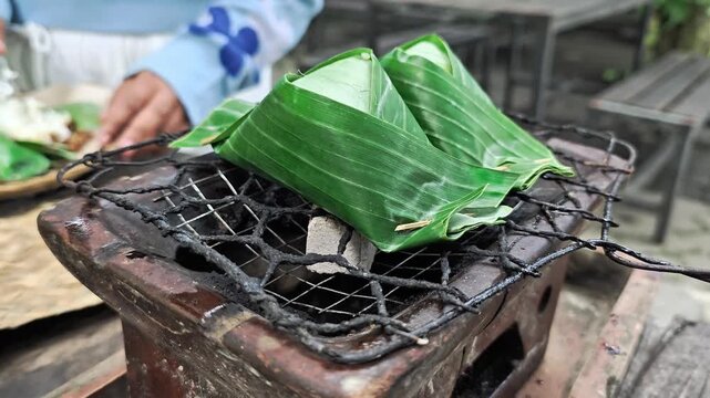 Preparing aromatic food called nasi bakar on a rustic charcoal grill outdoors