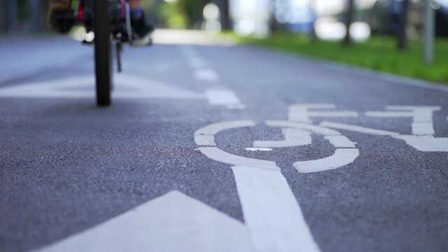 A young boy practices cycling in a public park. Camera captures only wheels and small legs. The ride is unstable and careful. Concept of learning balance, childhood development and outdoor training.