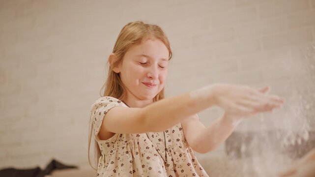 Child kneading pumpkin pie mixture calmly. Female youth shaping dough with focus in peaceful setting. Young girl diligently kneading pumpkin pie mixture amidst gentle light and flour dust in air
