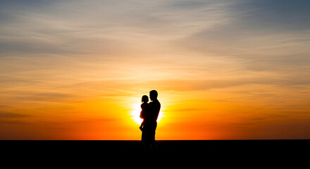 Obraz premium Silhouette of couple embracing at golden hour sunset over open field
