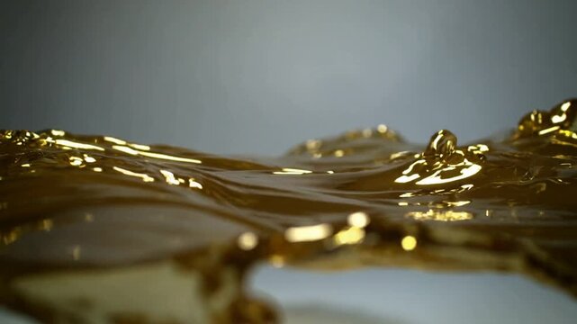 Sending initial left wave, gold viscous ribbon rippling in studio, showing specular highlights