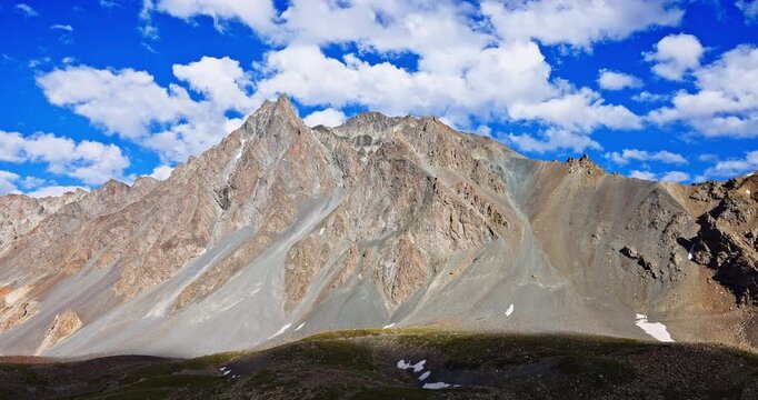 Majestic rocky mountain peaks under a clear blue sky with clouds, Tianshan range, Xinjiang, China.