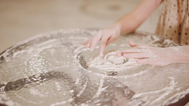 Overhead hands covered in flour, pie circle forming on round surface, playful messy motion, fingers shaping filling and pressing crust, rustic kitchen energy, seasonal spice aroma