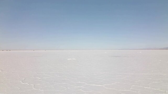Recording stationary camera capturing expansive salt flat at salt pan, with polygonal cracks
