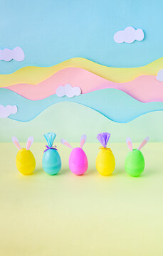 Colorful plastic Easter eggs with bunny ears in pastel studio scene for Happy Easter spring concept.