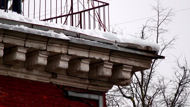 Worker carefully removes ice from ornate building ledge