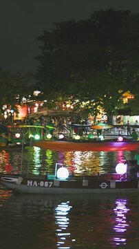 A boatman rows a traditional sampan boat along the Thu Bon River at night, a popular tourist activity.
