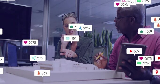 Woman pointing at model, man tapping tablet causing badges obscuring then fading, reviewing design