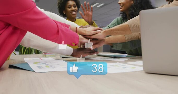 Colleagues placing hands on table in office, like-counter rising while icons floating, celebrating