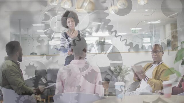 Standing woman speaker leading business meeting gesturing as gears overlaying tablet  and  guiding t