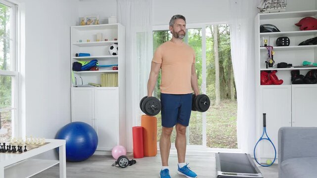 Fitness man exercising with dumbbells. Dumbbells strength training at home. Man doing dumbbells workout daily. Home gym workout with dumbbells.
